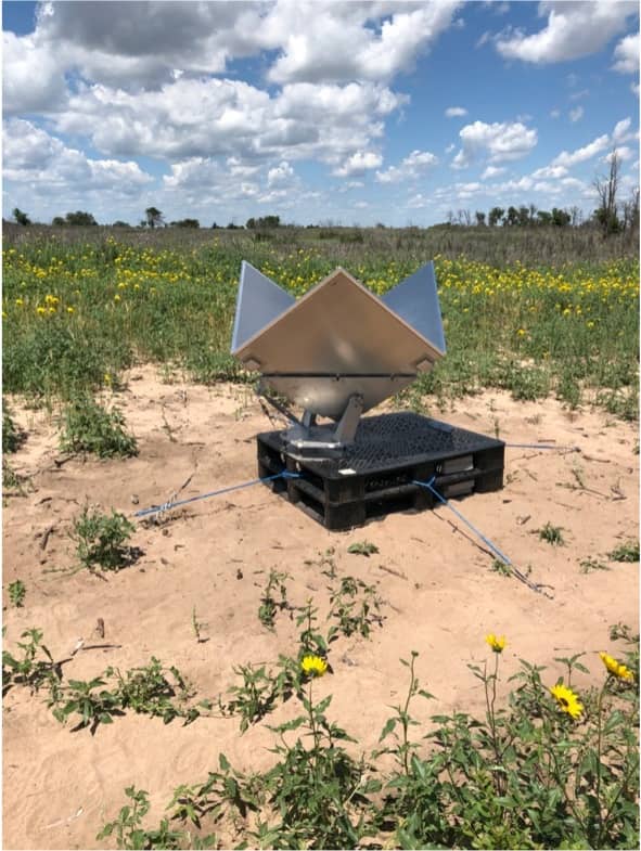 Metal corner reflector points at the sky in a grassy field