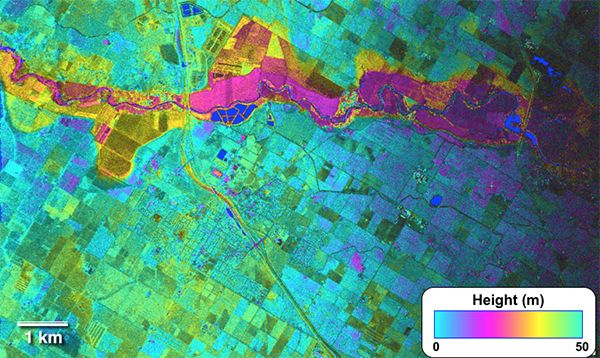 False-color radar image with rainbow fringes showing flooding snaking through the  middle of the plain